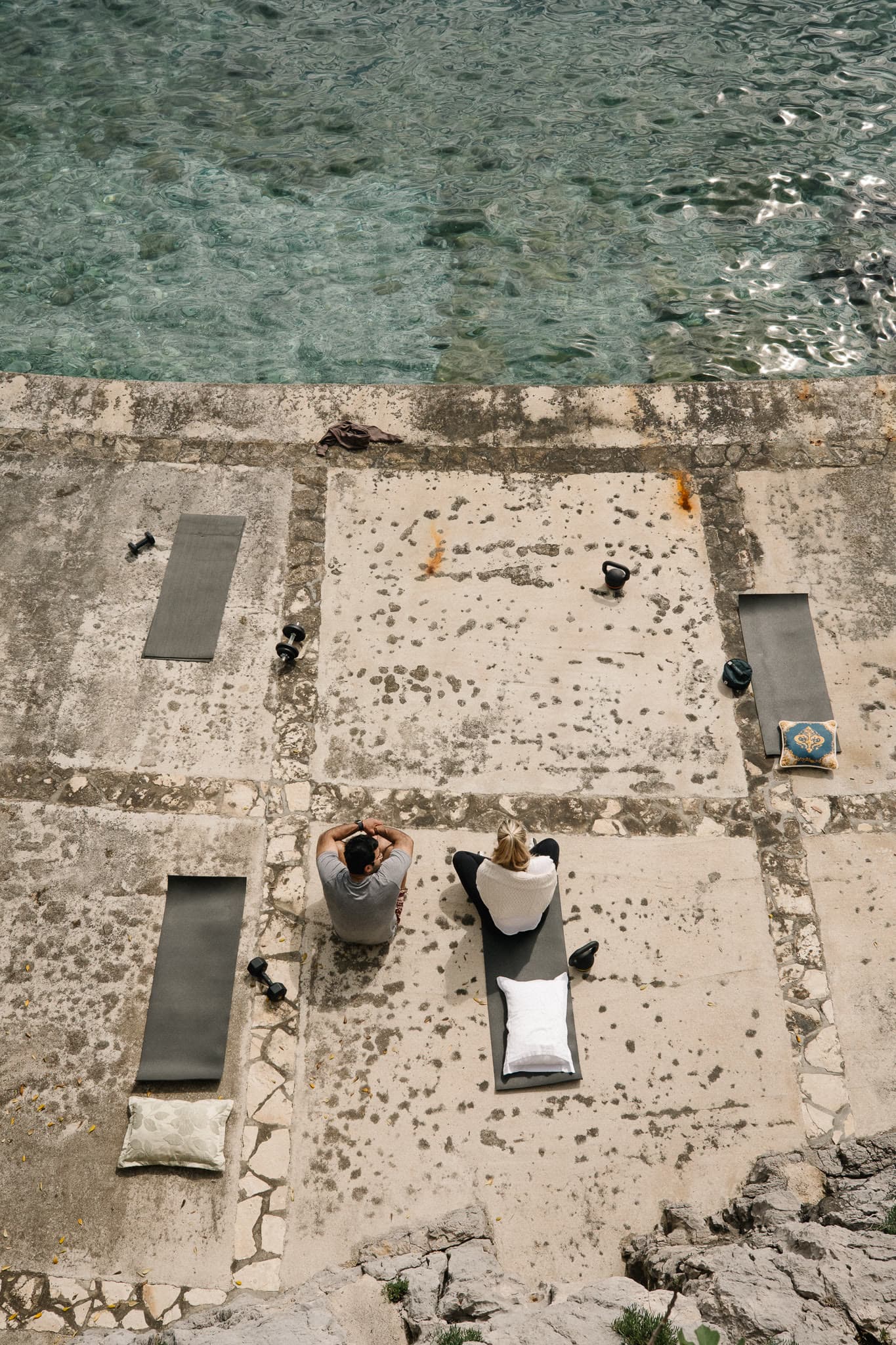 Mats, kettlebells, and the sea on a raw coastal terrace.