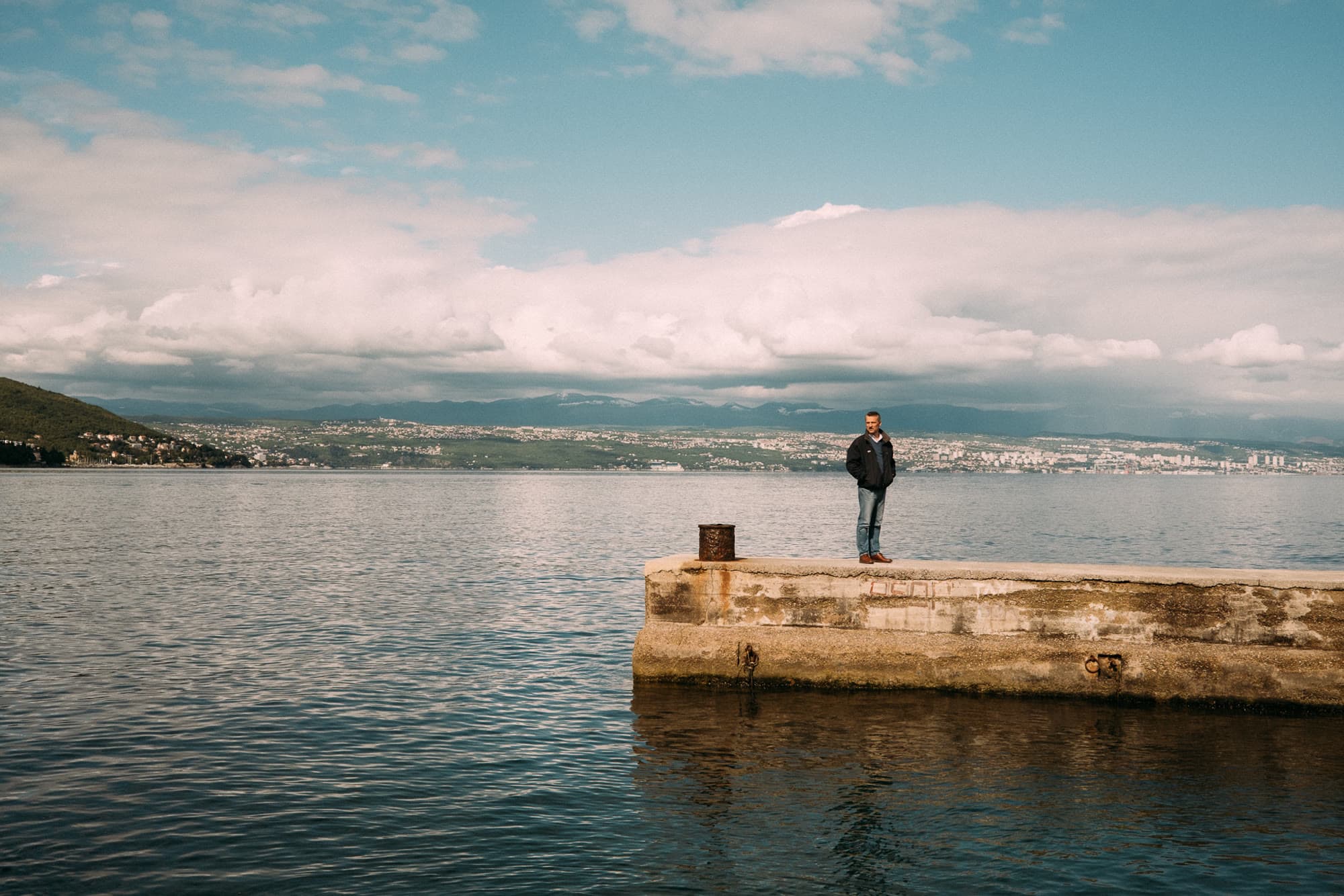 Richard Aceves standing on a weathered pier, looking out across the water.