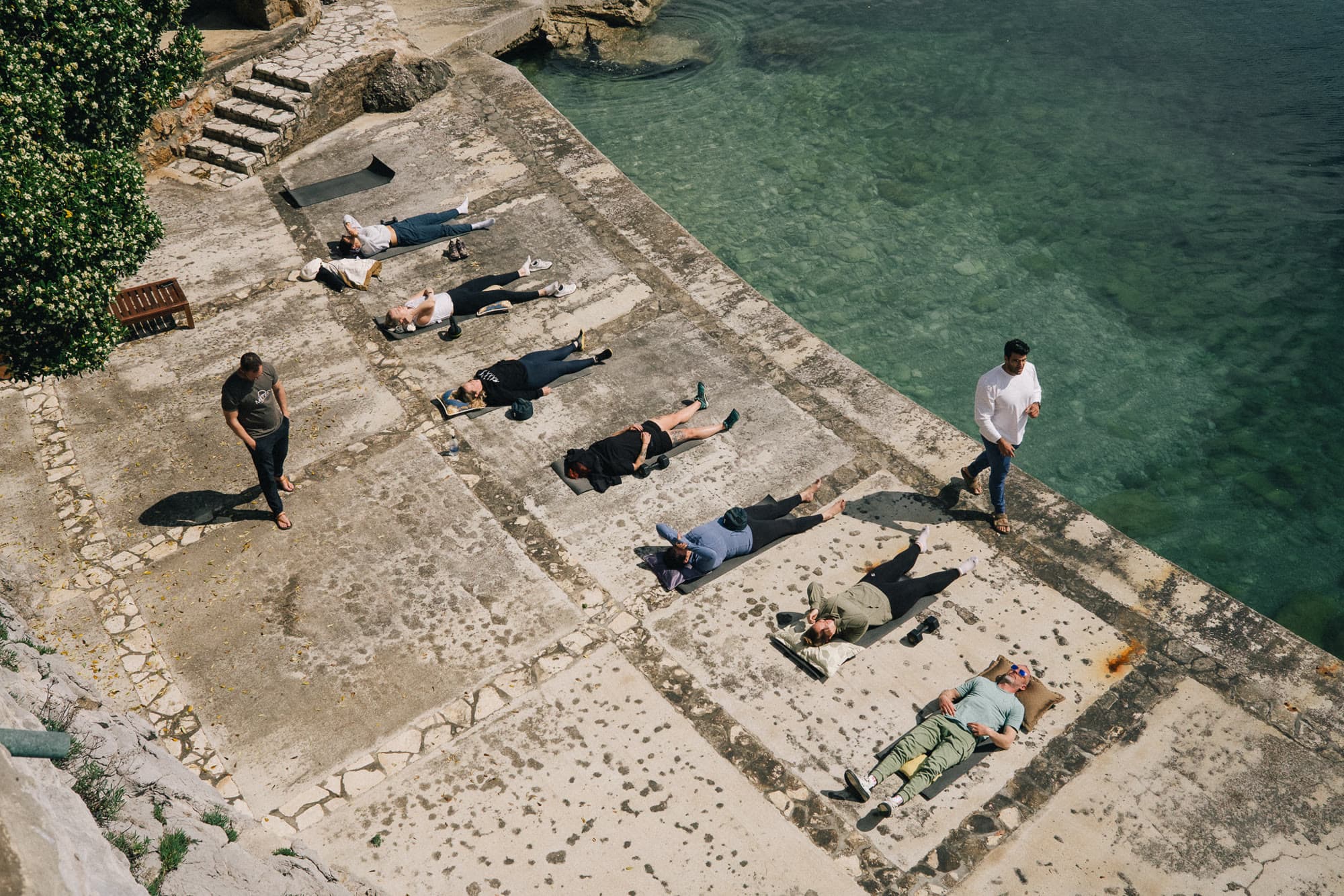 The group arranged along a coastal terrace, with facilitators moving among them.