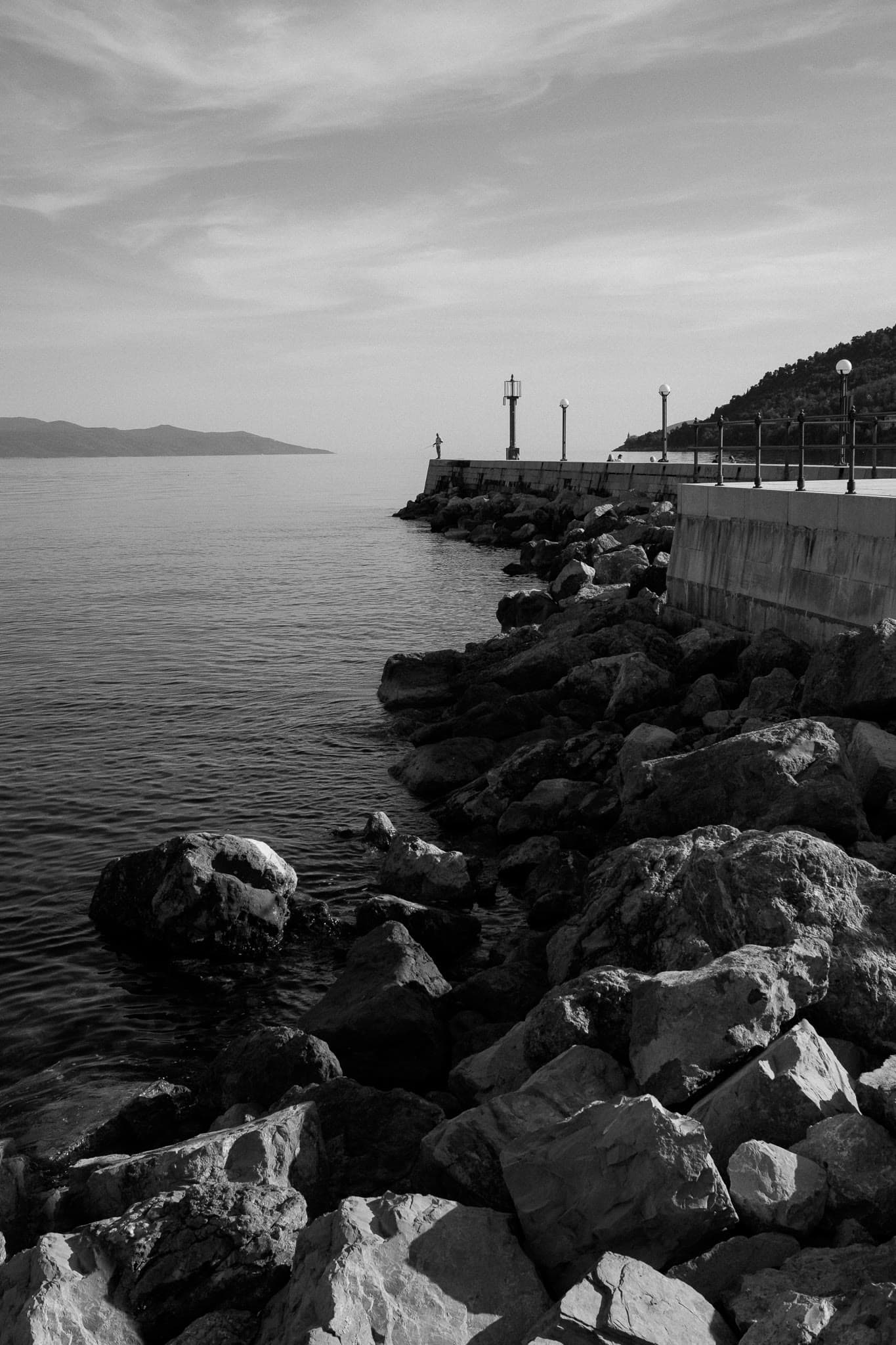 Rocks, a pier, and a single figure looking out.