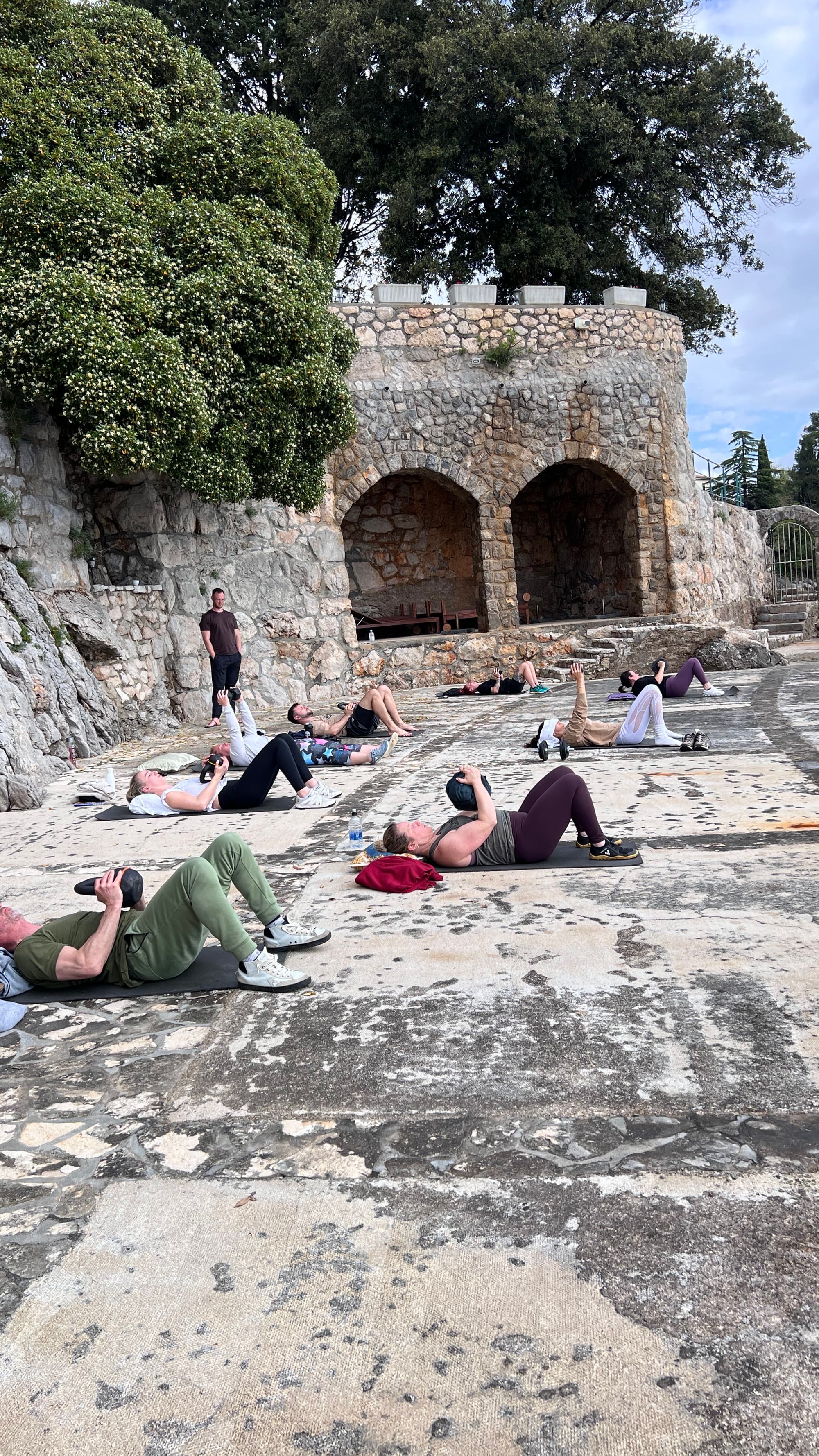 Participants on a stone plaza working with kettlebells and floor-based effort.